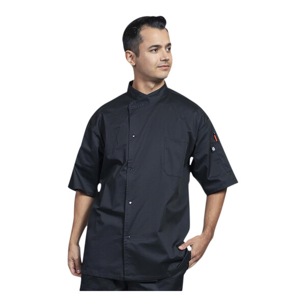 A man wearing a black Uncommon Chef Luca chef coat with black mesh on the back.