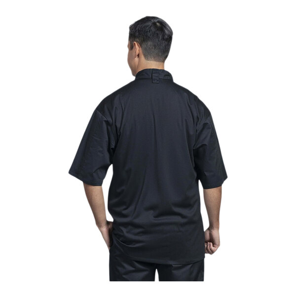 A man wearing a black Uncommon Chef Luca short sleeve chef coat with a black mesh back.