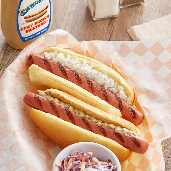 A Sabrett beef hot dog with onions and coleslaw on a paper plate.