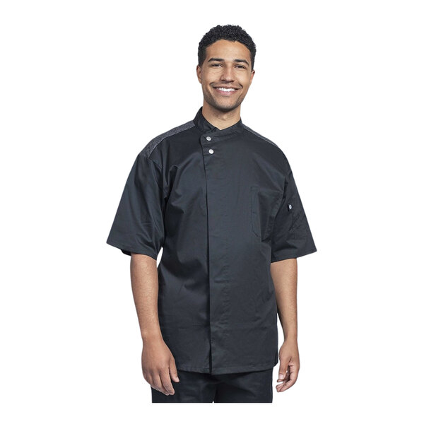 A man wearing a black Uncommon Chef short sleeve chef coat with silver mesh details.