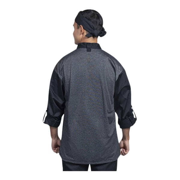 A man wearing a Uncommon Chef black and grey long sleeve chef coat with a silver mesh back.