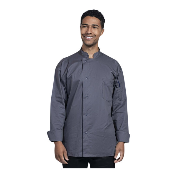 A man wearing a Uncommon Chef Turin long sleeve chef coat with a slate mesh back smiling in a professional kitchen.