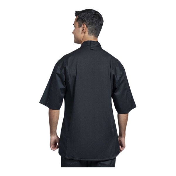 A man wearing a black Uncommon Chef Venice short sleeve chef coat with black mesh back.