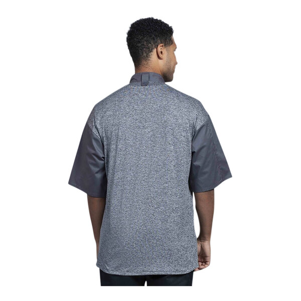 A man wearing a Uncommon Chef Modena short sleeve chef coat with grey mesh on the back.