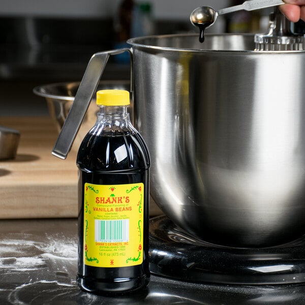 A person pouring Shank's Imitation Vanilla into a mixing bowl.