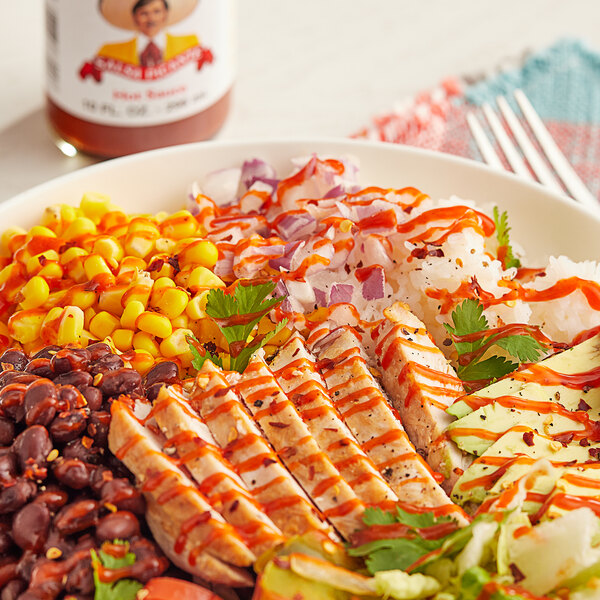 A plate of food with Tapatio hot sauce on a table.