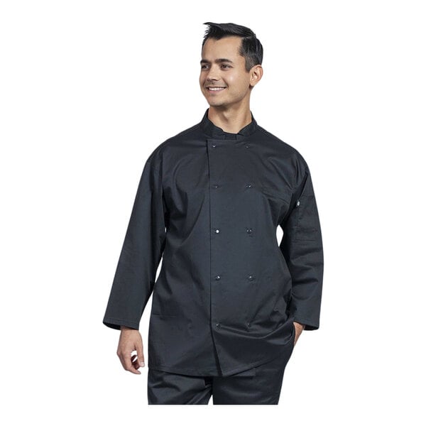 A man wearing a black Uncommon Chef chef coat with black mesh on the back and 3/4 sleeves is smiling.