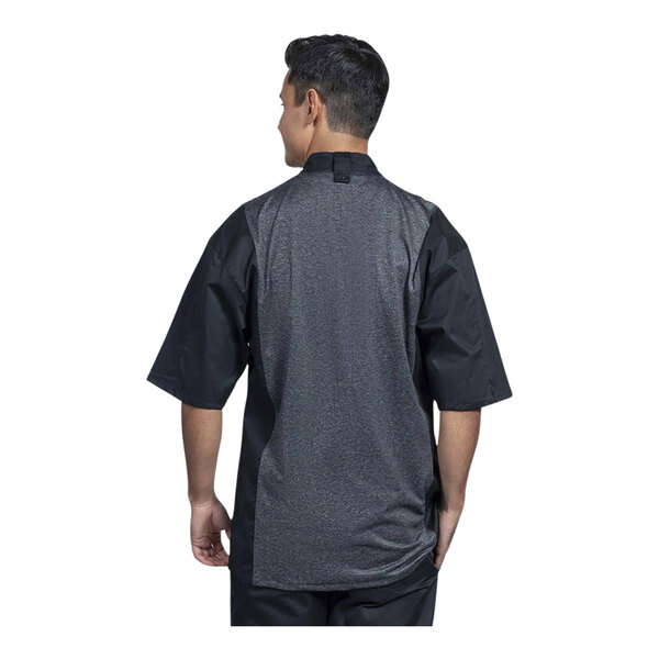 A man wearing a black Uncommon Chef chef coat with a silver heather mesh back.