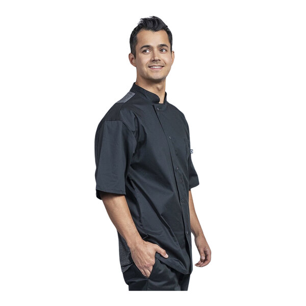A man wearing a Uncommon Chef black short sleeve chef coat with a silver mesh back.