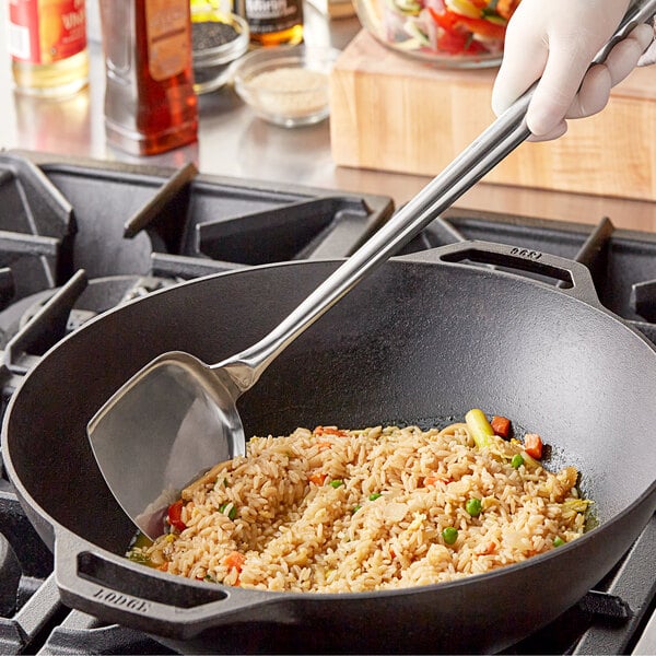 A person using a Town small stainless steel wok spatula to stir rice and vegetables in a pan.