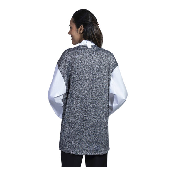 A woman wearing a white Uncommon Chef 3/4 sleeve chef coat with a black mesh back.