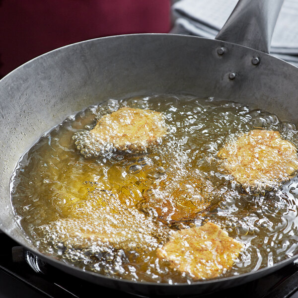 A frying pan with food cooking in olive oil.