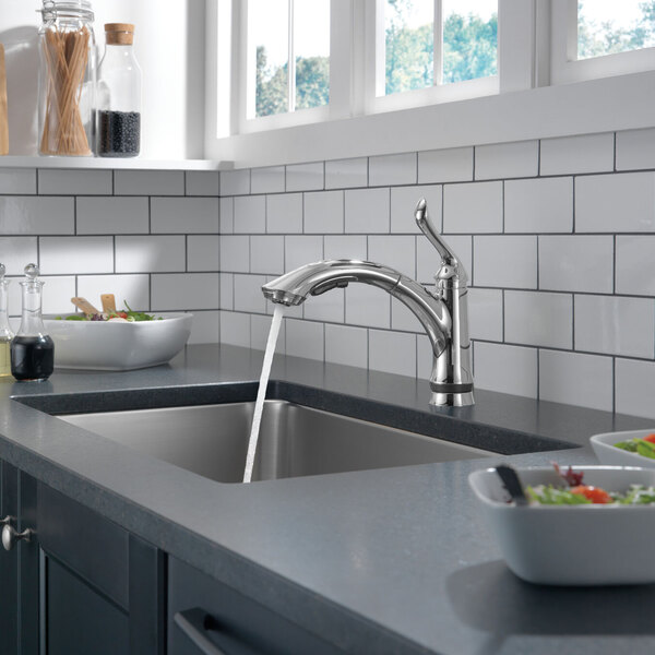 A Delta kitchen faucet on a counter over a sink.