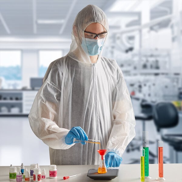 A man wearing white Lavex coveralls and gloves pouring liquid into a container.