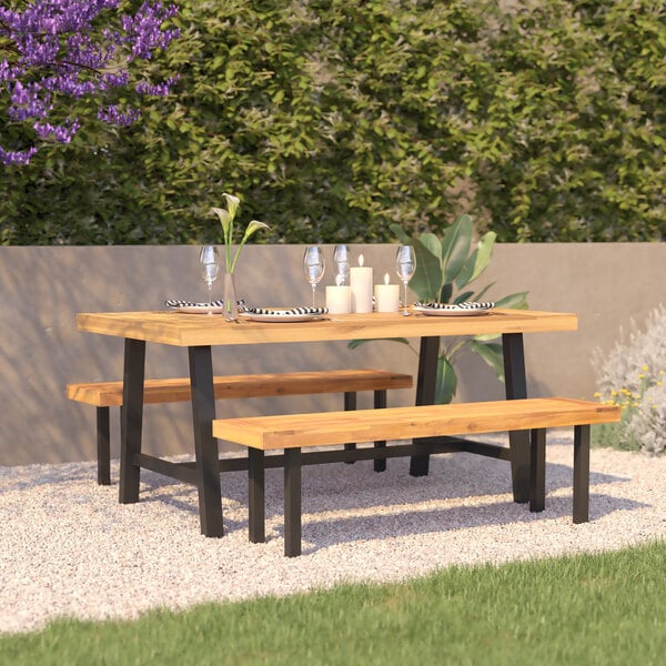 A Flash Furniture rectangular acacia wood table with matte black legs on an outdoor patio with a wooden bench.