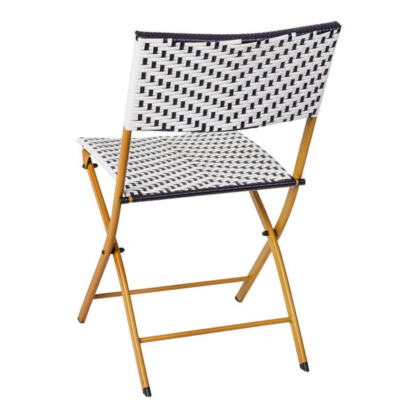 A Flash Furniture Rouen navy and white synthetic rattan folding chair with a natural steel frame with a black and white pattern.