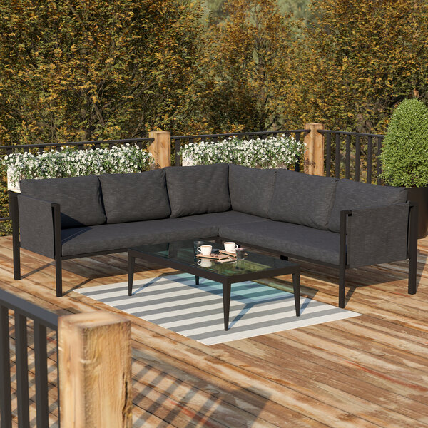 A Flash Furniture black outdoor sectional with charcoal cushions on a wooden deck.