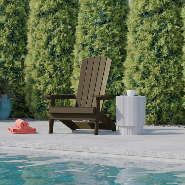 A brown Flash Furniture faux wood Adirondack chair sitting next to a pool.