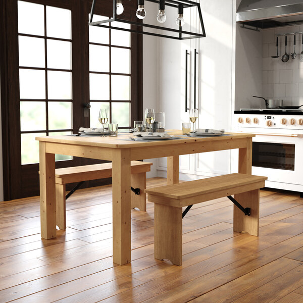 A wooden rectangular table with benches and plates in a home kitchen.