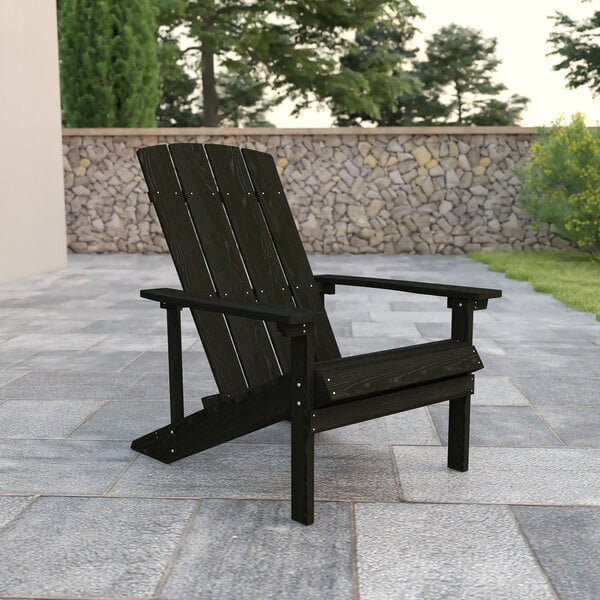 A black wooden Flash Furniture Charlestown Adirondack chair on a stone surface.