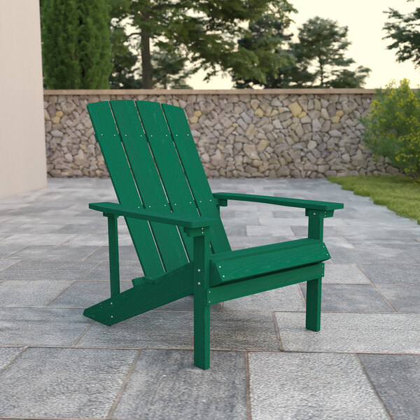 A Flash Furniture Charlestown green faux wood Adirondack chair on a stone surface.