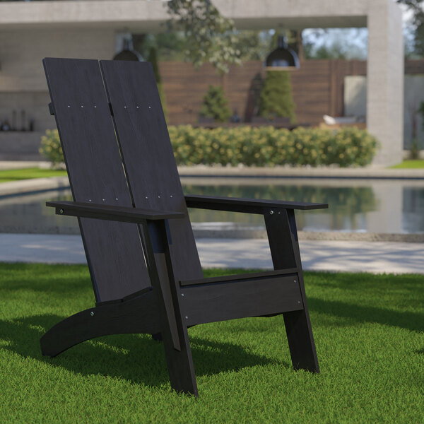 A Flash Furniture black faux wood Adirondack chair on grass.