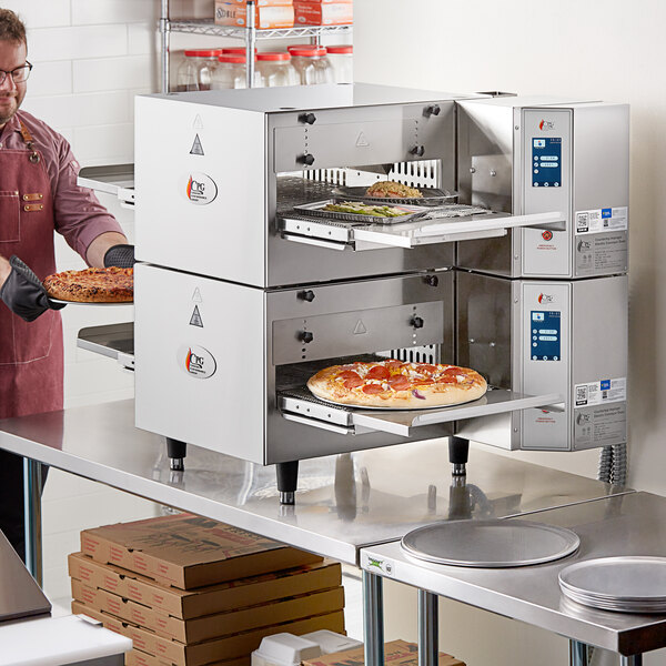 A man in a kitchen with a Cooking Performance Group countertop impinger conveyor oven.