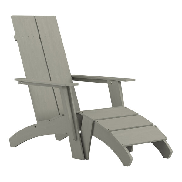 A gray wooden Adirondack chair with a foot rest.