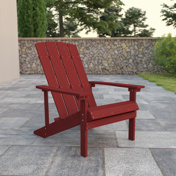 A red Flash Furniture Charlestown Adirondack chair on a stone patio.