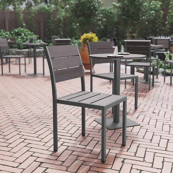 A Flash Furniture Finch Gray Faux Teak slat side chair and table on an outdoor patio.