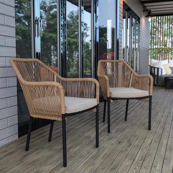 Two Flash Furniture Kallie natural wicker arm chairs with ivory cushions on a wood deck.