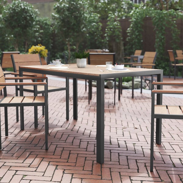 A Flash Furniture rectangular natural faux teak table and gray metal frame on a brick patio.