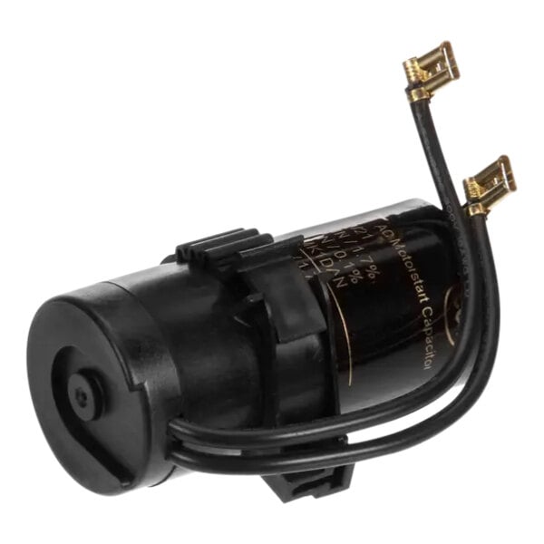 A close up of a black round Manitowoc Ice start capacitor with wires.