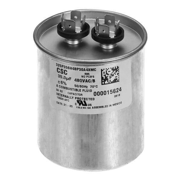 A round silver Manitowoc Ice run capacitor with black and white labels on it.