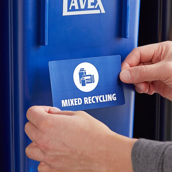 A person holding a Lavex mixed recycling label card and putting it into a blue recycling bin.