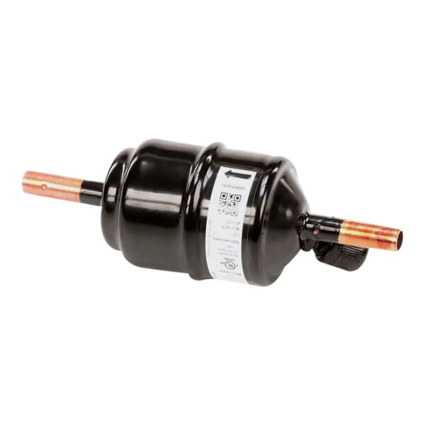 A black cylinder with copper pipes and a white label on a Manitowoc Ice filter drier.