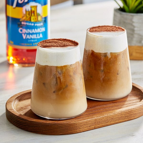 Two glasses of coffee with Torani Sugar-Free Cinnamon Vanilla syrup on a wooden tray.