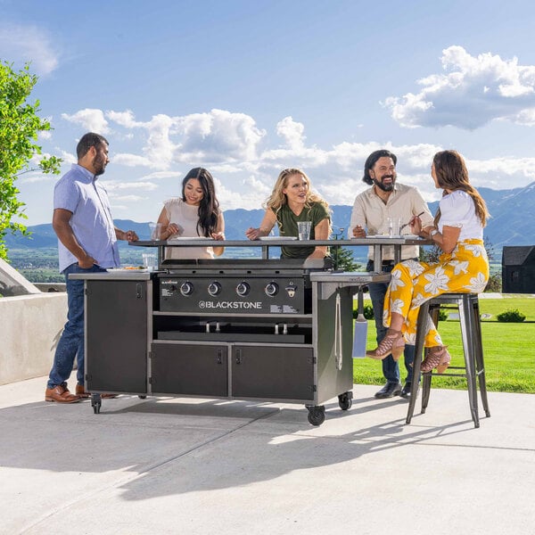A Blackstone outdoor griddle with 4 people sitting at a table.