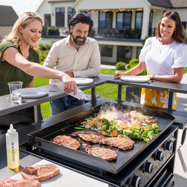 A group of people cooking food on a Blackstone Chef's Table outdoor griddle.