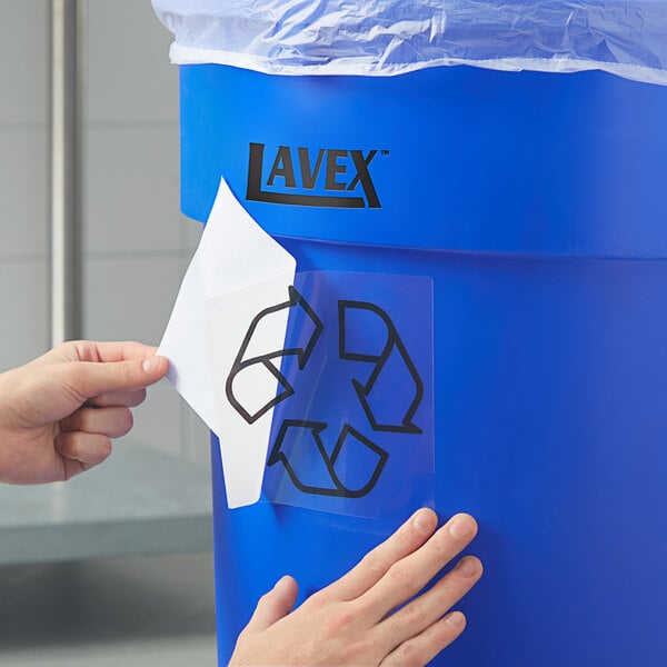 A hand putting a Lavex recycle label on a blue container.