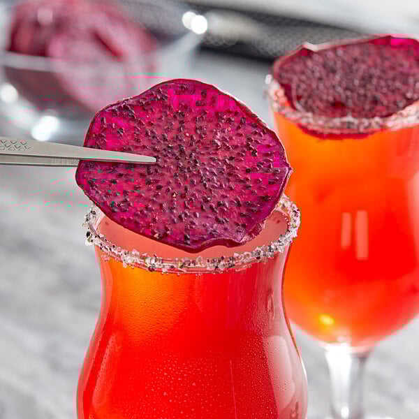 Two glasses of red and purple drinks with dried red dragon fruit slices on top.
