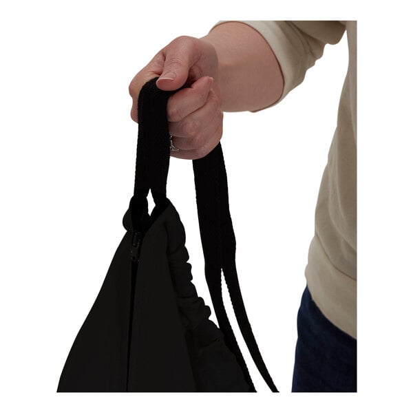A hand holding a black canvas laundry bag with a strap.