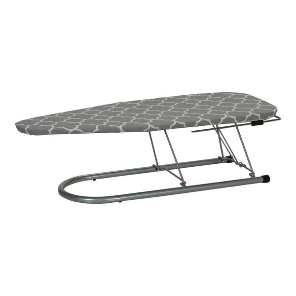 A Household Essentials steel mesh ironing board with a grey patterned cover and iron rest on a metal stand.