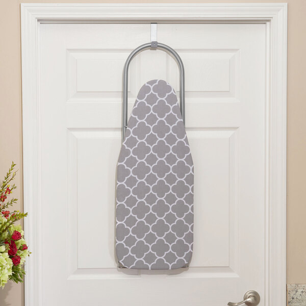 A white door with a steel mesh ironing board with a trellis pattern hanging on it.