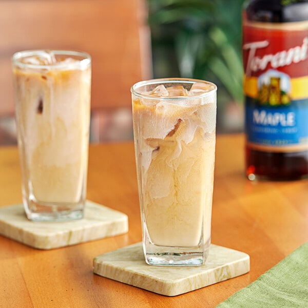 A glass of iced coffee with Torani Maple Flavoring Syrup on a coaster.