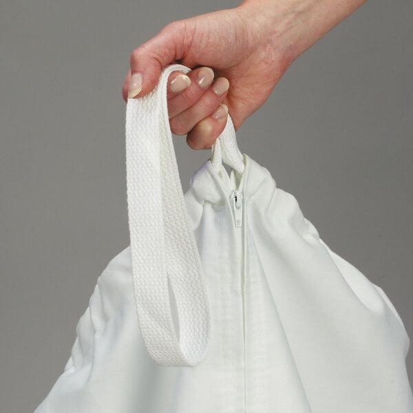 A hand holding a white canvas laundry bag with a white ribbon hanging from it.