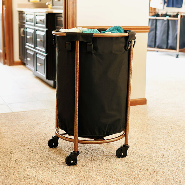 A black metal laundry hamper with wheels and a black bag on it.