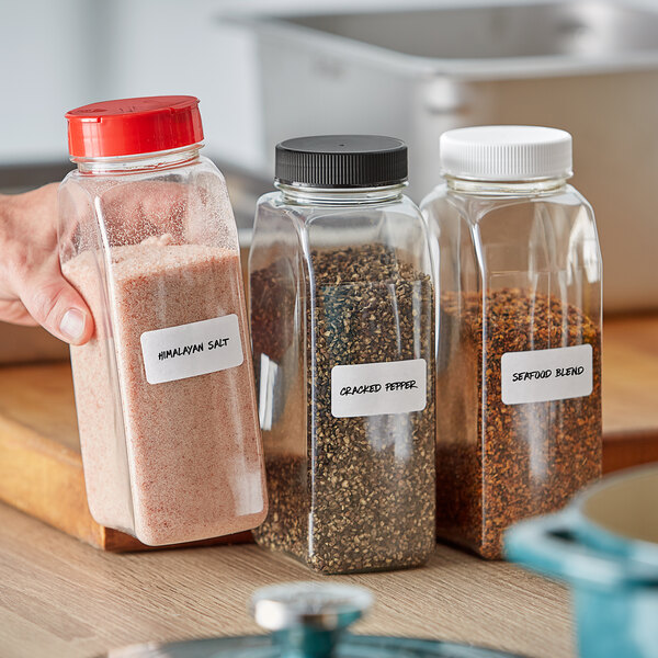 A hand holding a rectangular plastic spice container filled with pink salt.
