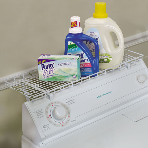 A white steel shelf over a washing machine with laundry detergents on top.