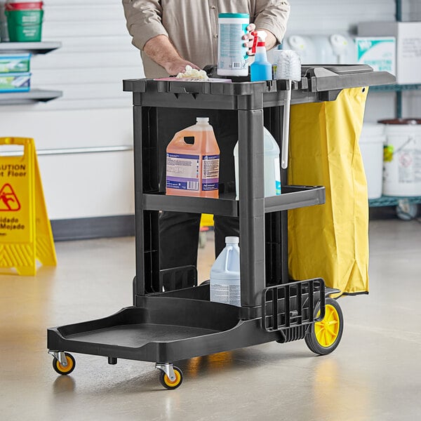 A man holding a Lavex Premium black and yellow janitor cart kit.